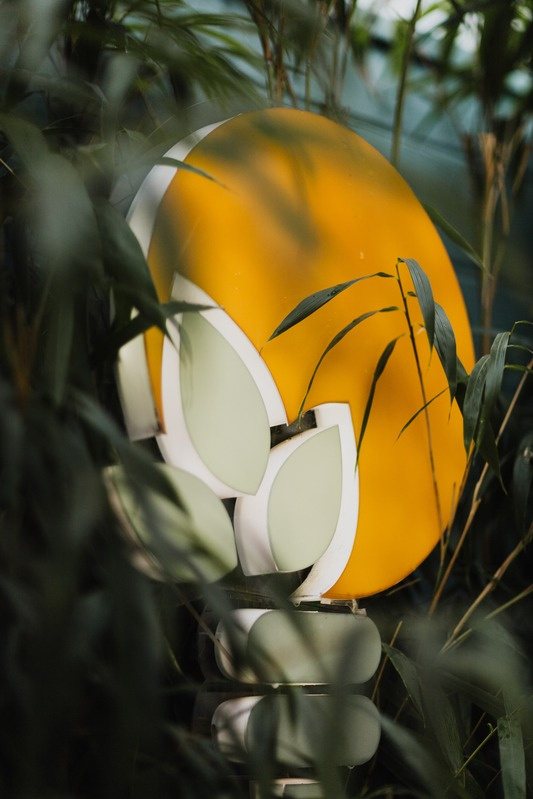 Escultura da marca Panaceia entre a vegetação da galeria